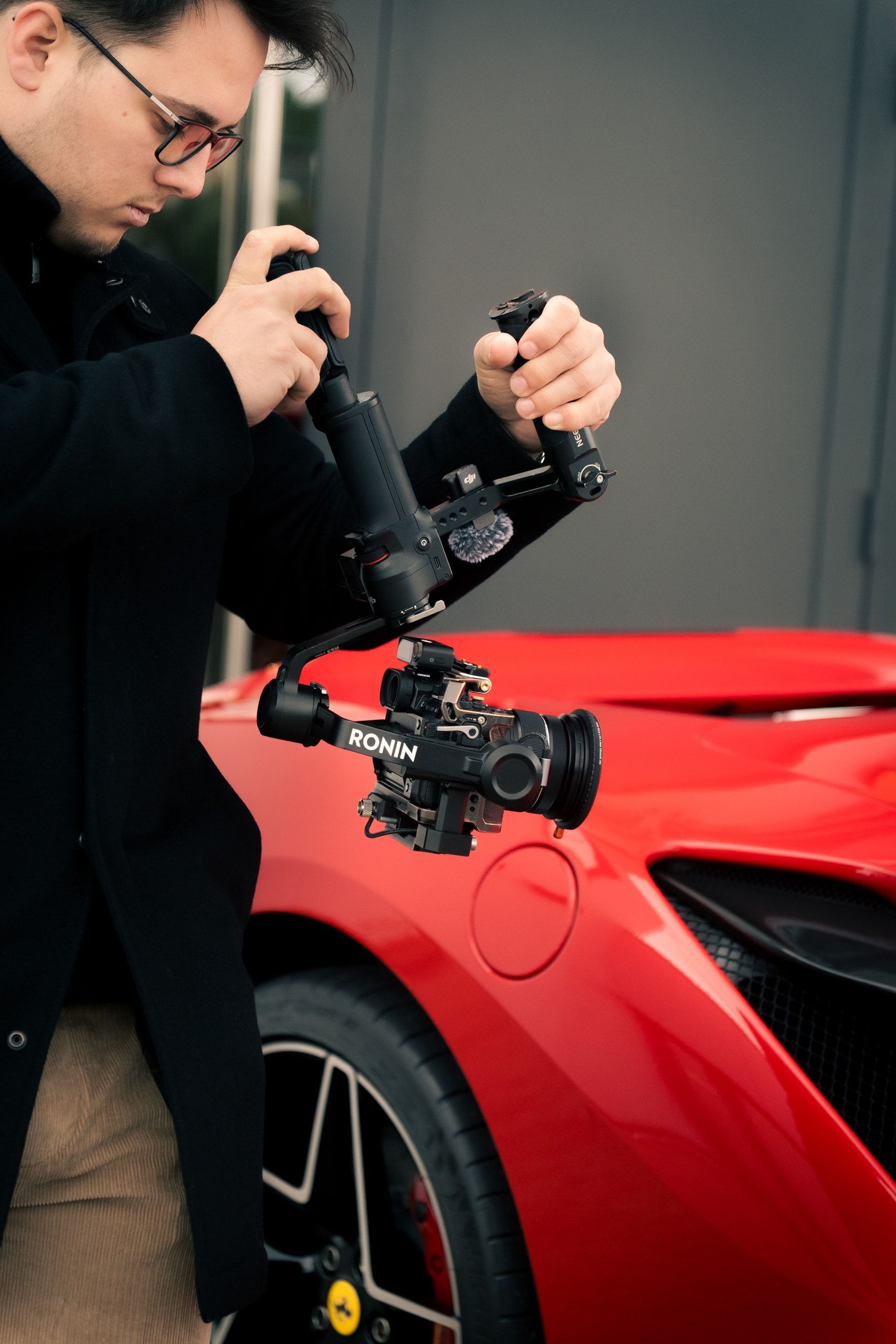 Vidéaste filmant une voiture de sport rouge au stabilisateur